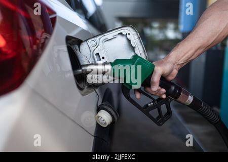 Primo piano del lavoratore in piedi sulla stazione di servizio e auto di rifornimento. Foto Stock