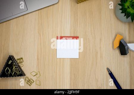 Una vista dall'alto di un blocco note per note importanti su una scrivania stipata Foto Stock
