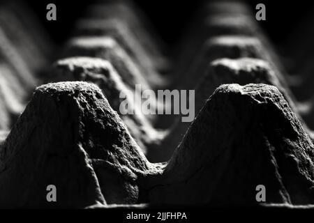 Angolo basso, estrema chiusura di un vassoio vuoto per uova di cartone immagine monocromatica, astratta e scura della struttura e del disegno di un cartone. Selez Foto Stock