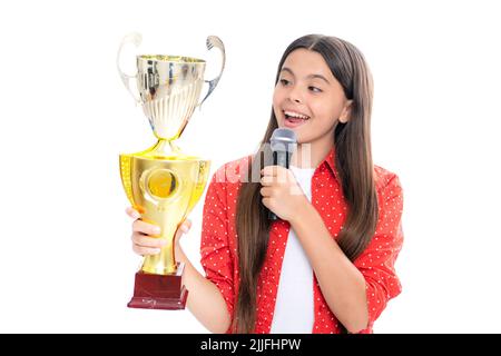 Ragazza adolescente con la tazza di vincita. Teen che tiene un discorso del microfono del trofeo. Bambino vincitore del capretto ha vinto la concorrenza, celebrando il successo e la vittoria. Foto Stock