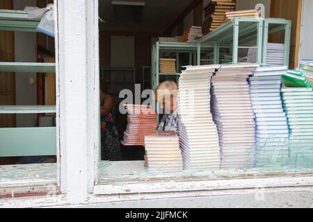 REGIONE DI KHARKIV, UCRAINA - 25 LUGLIO 2022 - le donne si trovano accanto alle pile di libri di testo in una scuola rovinata dall'abbattimento delle truppe russe, Chuhuiv distric Foto Stock