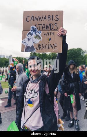 05.28.2022 Varsavia, Polonia. Colpo verticale all'aperto di un manifestante caucasico che lotta per la marijuana legale e che tiene un cartellone che dice - cannabis sta con l'Ucraina. Foto di alta qualità Foto Stock