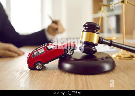 Piccola automobile giocattolo sul tavolo dell'avvocato che illustra il concetto di incidente dell'automobile e di causa Foto Stock