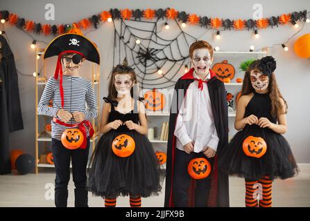 Gruppo di bambini in diversi costumi di Halloween spooky che tengono cesti di zucca Foto Stock