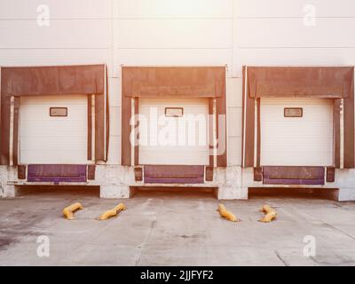 In un edificio bianco del magazzino, sono presenti tre porte automatiche per lo scarico delle merci. Foto Stock