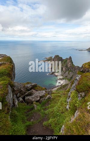 Måtind vedere un mare roccioso che lo costellano. Vista dalla cima di una montagna vicino al mare di Norvegia con ripide scogliere, spiaggia di sabbia bianca e una vegetazione. Foto Stock