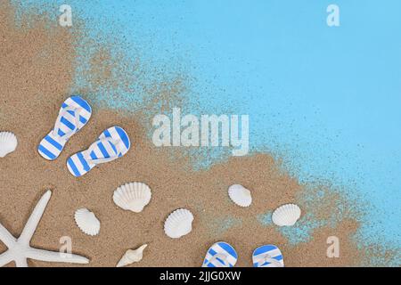 Scarpe estive, conchiglie, stelle marine e sabbia in un angolo di sfondo blu Foto Stock