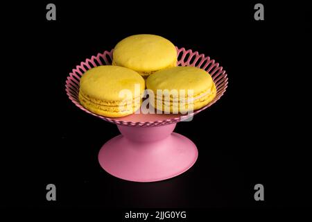 Macaroni gialli su sfondo nero pasta francese. Pila di macaron giallo con isolato su sfondo nero scuro. Macaroon. Foto Stock