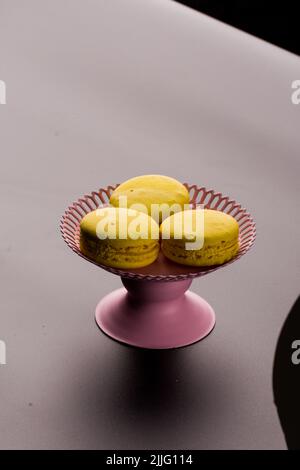Macaroni gialli su sfondo nero pasta francese. Pila di macaron giallo con isolato su sfondo nero scuro. Macaroon. Foto Stock