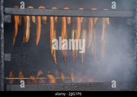 26 luglio 2022, Schleswig-Holstein, Lübeck-Travemünde: Il pesce è affumicato in un fumatore nel porto di pesca. Foto: Marcus Brandt/dpa Foto Stock