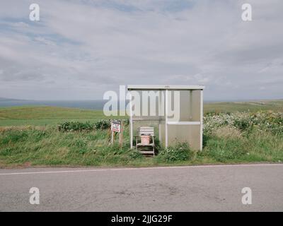 Una fermata remota del bus rifugio e posta box nel paesaggio estivo della costa nord-occidentale della penisola di Trotternish, Kilmuir, Isola di Skye, Scozia Foto Stock