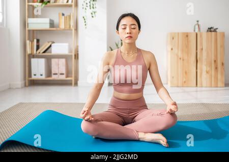 Giovane donna asiatica seduta sul tappeto lotus posa fare yoga esercizio Foto Stock