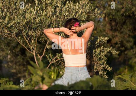 Vista posteriore di una donna che tiene i capelli in su alla natura Foto Stock