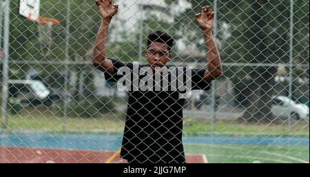 Sconvolto l'uomo africano appoggiato su una recinzione metallica. Arrabbiato persona nera scuotendo recinzione Foto Stock