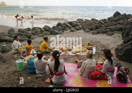 Lombok, Indonesia - la gente indù mangia insieme il cibo dopo un rituale alla spiaggia pura Batu Bolong. Foto Stock