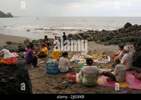 Lombok, Indonesia - la gente indù mangia insieme il cibo dopo un rituale alla spiaggia pura Batu Bolong. Foto Stock