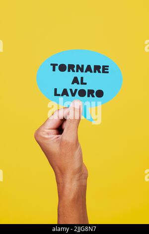 l'uomo ha un segno di carta blu a forma di fumetto con il testo scritto in italiano, su sfondo giallo Foto Stock