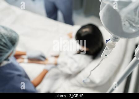 Inquadratura selettiva ad angolo alto di una donna irriconoscibile che ha una terapia endovenosa in ospedale Foto Stock