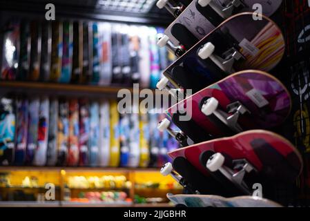 Molti surfskate appesi sulla parete del negozio dello skateboard. Molti colori vivaci. Foto Stock