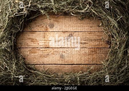 Telaio da fieno di paglia secco su tavola di legno d'epoca. Sfondo villaggio rurale Foto Stock