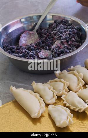 Mirtilli per gnocchi. Cosparso di zucchero. Nelle vicinanze si trovano i gnocchi appiccicosi. Primo piano. Foto Stock