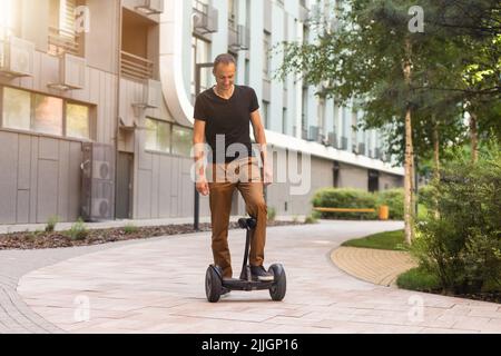 Persona che corre un hoverboard su un sentiero pubblico, ora sono vietati in tutti i luoghi pubblici Foto Stock