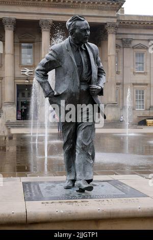 La statua di un uomo che camminava si trovava su un terreno di pietra fuori dalle fontane della stazione ferroviaria di Huddersfield nel terreno intermedio Foto Stock