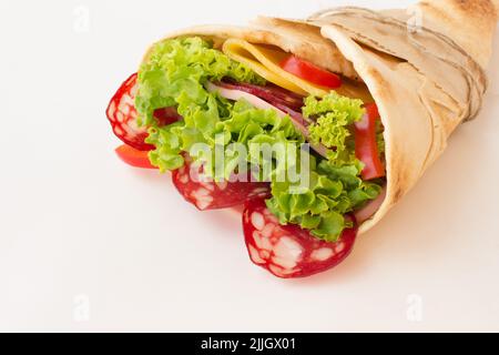 Arrotolate la tortilla con le erbe, il formaggio e la carne su uno sfondo bianco Foto Stock