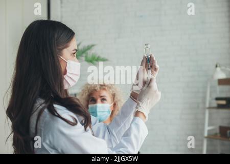 L'infermiere preleva il farmaco dal flaconcino prima di somministrare l'iniezione al paziente, in ospedale. Vaccinazione contro il coronavirus. Prevenzione del coronavirus. Pandemia Foto Stock