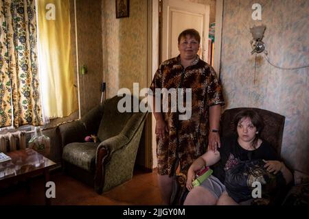 19 luglio 2022, Slovyansk, Ucraina: Madre Svetina insieme alla sorella disabili Katalina seduta sul divano, poiché ha solo lo stesso sviluppo di una ragazza di 5 anni, i figli di Svetina sono ora stati lasciati nella parte occidentale del paese. Sebbene l'avanzata russa si stia avvicinando sempre più, alcuni cittadini slovacchi per vari motivi hanno deciso di restare indietro. Slovyansk con una popolazione di 106.972 abitanti (2021 est.), ora si erge come principale città strategica nella regione di Donetsk, Donbas, poiché la città è stata continuamente pesantemente bombardata da artiglieri e missili russi, sin dal Foto Stock