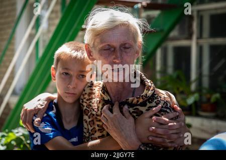 19 luglio 2022, Slovyansk, Ucraina: Madre Rita grida mentre suo figlio Igor la abbraccia, ora si prende cura di altre famiglie come le bombe al fosforo distruggono la loro casa a Krasnopolye, Donbas. Ora vivevano in condizioni prive di elettricità, acqua e gas. Sebbene l'avanzata russa si stia avvicinando sempre più, alcuni cittadini slovacchi per vari motivi hanno deciso di restare indietro. Slovyansk con una popolazione di 106.972 abitanti (2021 est.), ora si erge come una città strategica principale nella regione di Donetsk, Donbas, in quanto la città è stata continuamente pesantemente bombardata da artiglierie russe e missil Foto Stock