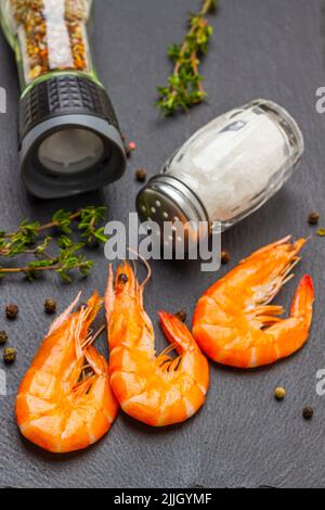 Gamberetti, sale in vaso di vetro, spezie e rametti di timo su nero. Disposizione piatta Foto Stock