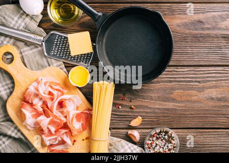 Ingredienti pancetta uovo parmigiano formaggio per la cottura della carbonara italiana, fondo di legno scuro Foto Stock