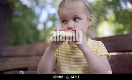 Odessa, Ucraina, Europa dell'Est. 26th luglio 2022. Primo piano di ragazza carina mangia gelato. Primo piano della bambina seduta sul panca del parco e mangiare il icecream. (Credit Image: © Andrey Nekrasov/ZUMA Press Wire) Foto Stock