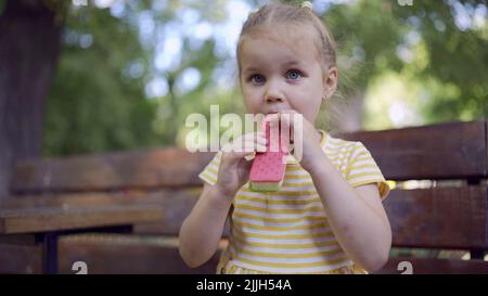 Odessa, Ucraina, Europa dell'Est. 26th luglio 2022. Primo piano di ragazza carina mangia gelato. Primo piano della bambina seduta sul panca del parco e mangiare il icecream. (Credit Image: © Andrey Nekrasov/ZUMA Press Wire) Foto Stock