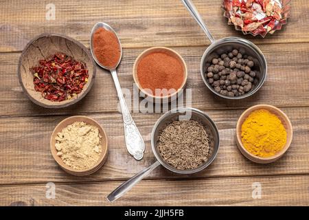 Zenzero macinato, paprika e curcuma in ciotole. Spezie secche. Vista dall'alto. Sfondo in legno Foto Stock