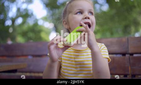 Odessa, Ucraina, Europa dell'Est. 26th luglio 2022. Primo piano di ragazza carina mangia gelato. Primo piano della bambina seduta sul panca del parco e mangiare il icecream. (Credit Image: © Andrey Nekrasov/ZUMA Press Wire) Foto Stock