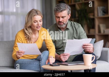 Alfabetizzazione finanziaria. Occupato marito e moglie di mezza età calcolando il bilancio della famiglia insieme Foto Stock