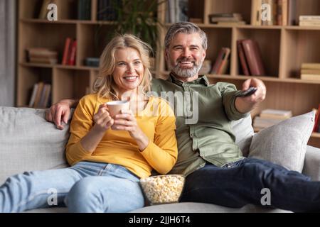 Casa relax. Felice sposato coppia di mezza età guardando la TV in soggiorno Foto Stock
