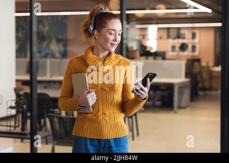 Donna d'affari caucasica adulta fidata che usa lo smartphone mentre è in ufficio Foto Stock