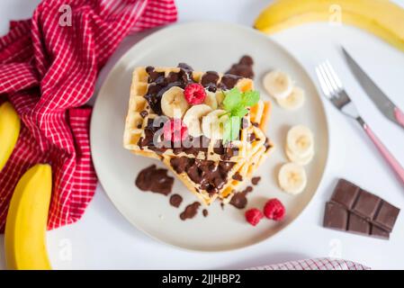 deliziosi waffle belgi da colazione con fragole e lamponi, cioccolata e banana Foto Stock