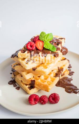 deliziosi waffle belgi a colazione con fragole, lamponi e cioccolato Foto Stock