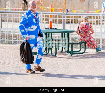 L'uomo con un costume da nuvola passa accanto a un tavolo da picnic presso la zona fieristica durante il New Orleans Jazz and Heritage Festival 2022 a New Orleans, LOUISIANA, USA Foto Stock