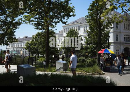 New York, NY, USA - 25 luglio 2022: Turisti a Battery Park con il molo A non occupato sul fiume Hudson visibile sullo sfondo Foto Stock