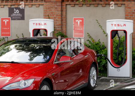 Poznan, Polonia. 26 lug 2022: Le auto elettriche Red Tesla integrano la batteria della stazione di ricarica, energia alternativa. Stazione di ricarica rapida Foto Stock