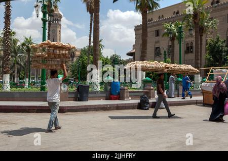 Gli uomini egiziani trasportano pane appena sfornato sulle loro teste su una strada adiacente al Bazaar di Khan el-Khalili al Cairo in Egitto. Foto Stock