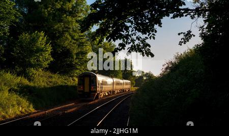 Treno sprinter di classe 158 della Northern Rail che si dirige verso il tramonto sulla piccola linea ferroviaria nord-occidentale nel North Yorkshire, Regno Unito Foto Stock