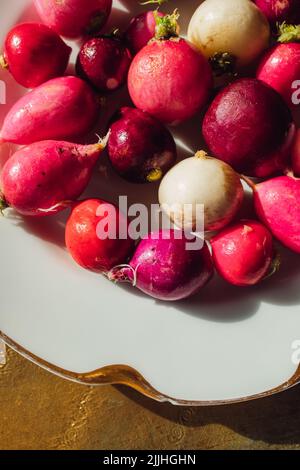 rifinito rosa, rosso, viola, bianco irradia su piastra bianca con oro Foto Stock