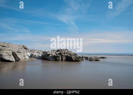 Ogmore-by-Sea Beach, Ogmore-by-Sea, vale of Glamorgan - rocce, acqua liscia e cieli blu Foto Stock