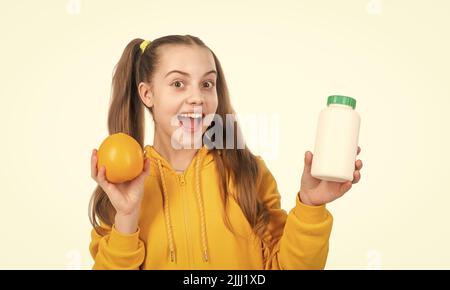 ragazza felice teen scegliere tra frutta d'arancia e pillola di vitamina isolato su bianco, supplemento minerale. Foto Stock